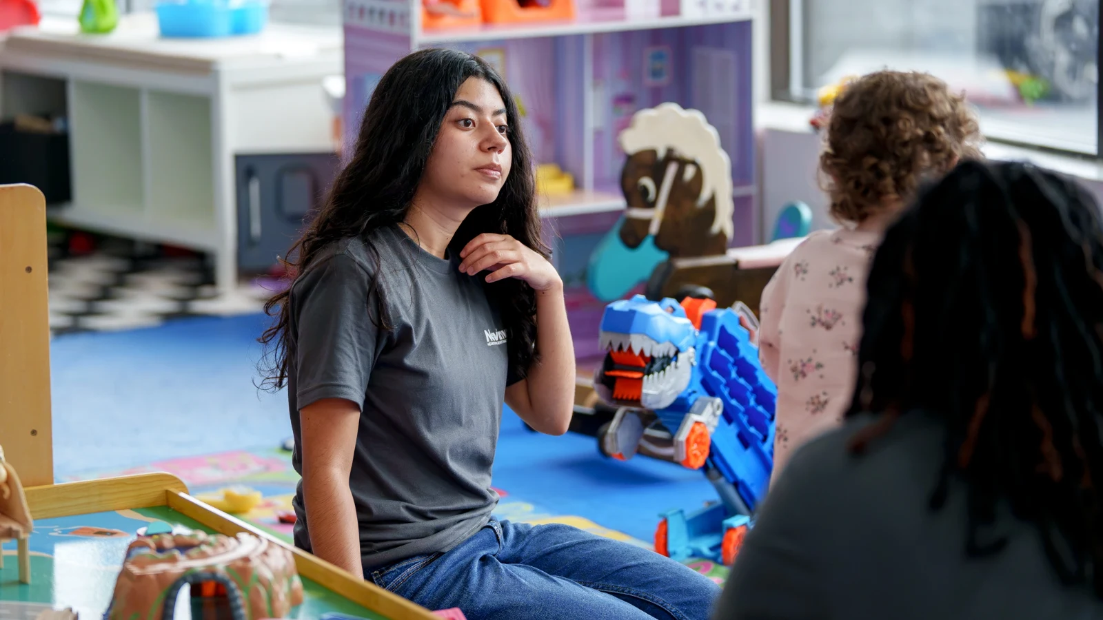 A Care Specialist sitting with children in a playroom