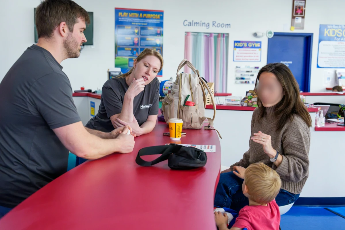 Two Novinway team members at a table talking through next steps with a parent, her son beside her