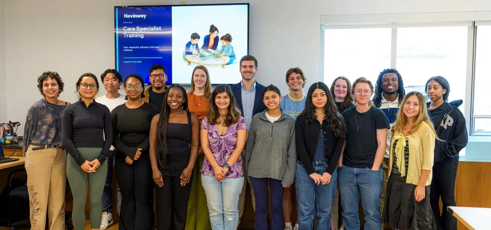 About twenty Novinway Care Specialists and clinical team members standing together in a training room, under a screen reading Care Specialist Training